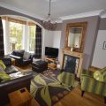 Living room with a large TV. There are two arm chairs and one long sofa