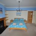 Double bed in a large bedroom with a TV in the corner