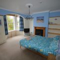 Double bed in a large bedroom with a TV in the corner