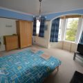Double bed in a large bedroom with a TV in the corner