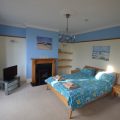Double bed in a large bedroom with a TV in the corner